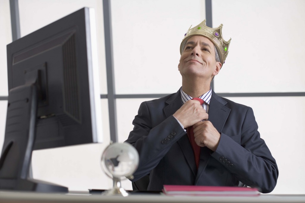 Businessman with crown sitting at desk