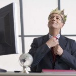 Businessman with crown sitting at desk